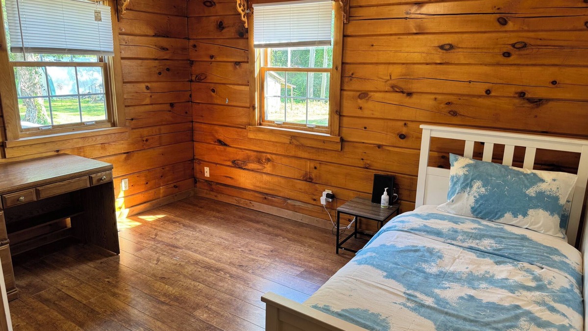 Dunnville House | Serene log home on spacious land with trees and a small farm.